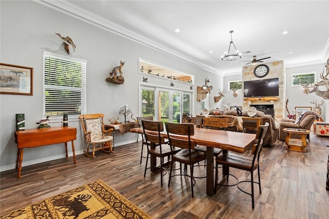 dining space with dark hardwood / wood-style flooring, ceiling fan with notable chandelier, a fireplace, and ornamental molding