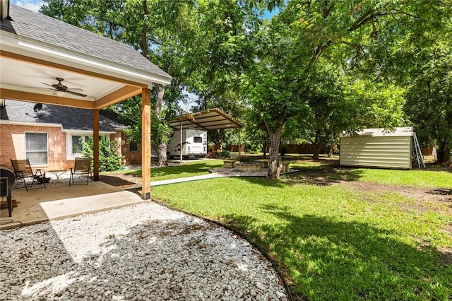 view of yard with a shed, a patio, and ceiling fan