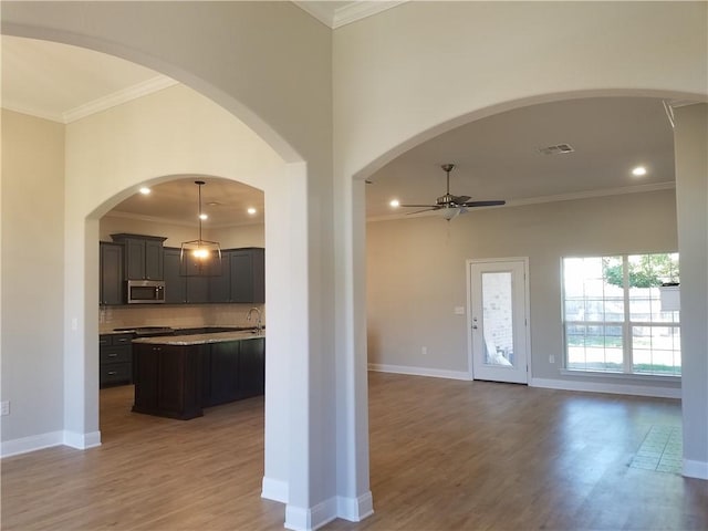 kitchen with ceiling fan, a kitchen island, ornamental molding, and light wood-type flooring