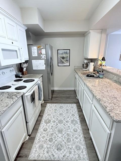 kitchen with dark wood-type flooring, sink, white cabinetry, white appliances, and light stone countertops