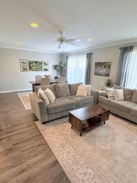 living room featuring crown molding, ceiling fan, and light wood-type flooring