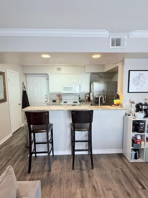 kitchen with a kitchen bar, white cabinetry, range, stainless steel fridge with ice dispenser, and dark hardwood / wood-style flooring