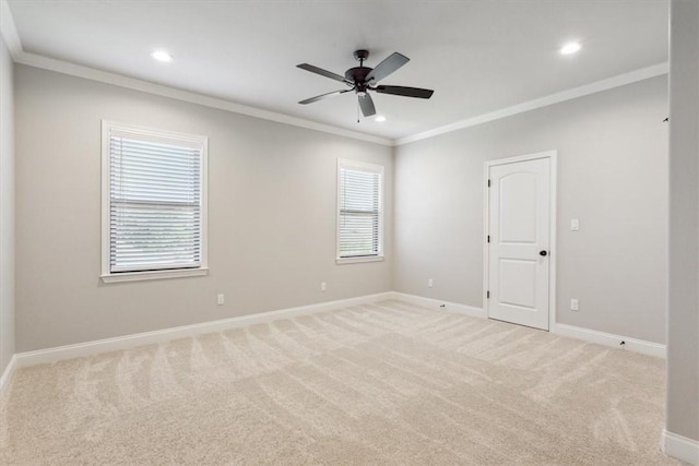 empty room with light colored carpet, crown molding, ceiling fan, and a healthy amount of sunlight