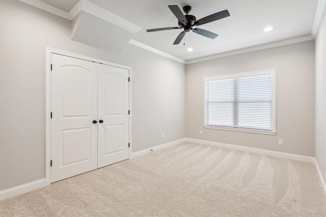 unfurnished bedroom with ceiling fan, crown molding, light carpet, and a closet