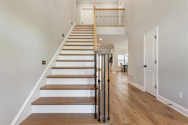 stairway featuring a high ceiling and hardwood / wood-style flooring