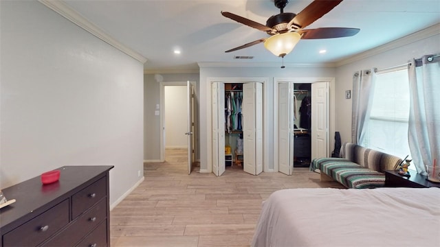 bedroom featuring ceiling fan, crown molding, two closets, and light wood-type flooring