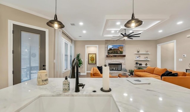 interior space featuring light stone countertops, a stone fireplace, sink, and decorative light fixtures