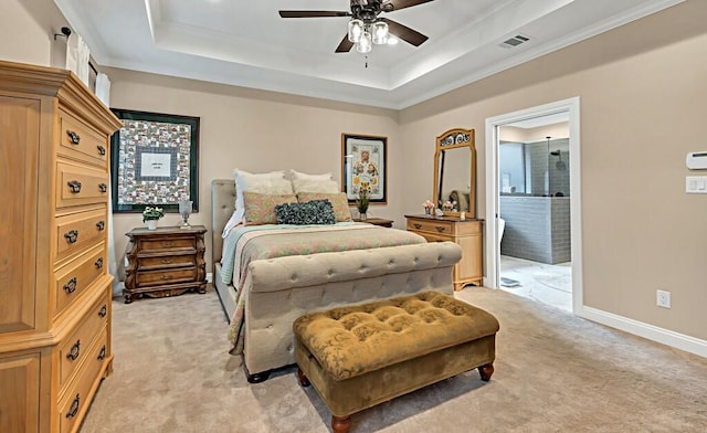 carpeted bedroom with crown molding, ceiling fan, ensuite bathroom, and a tray ceiling