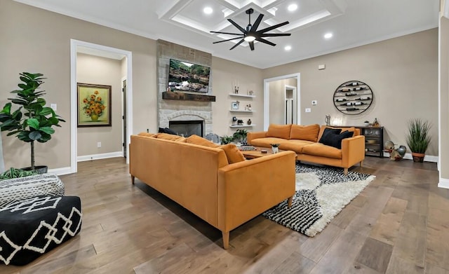 living room featuring crown molding, ceiling fan, coffered ceiling, a fireplace, and wood-type flooring