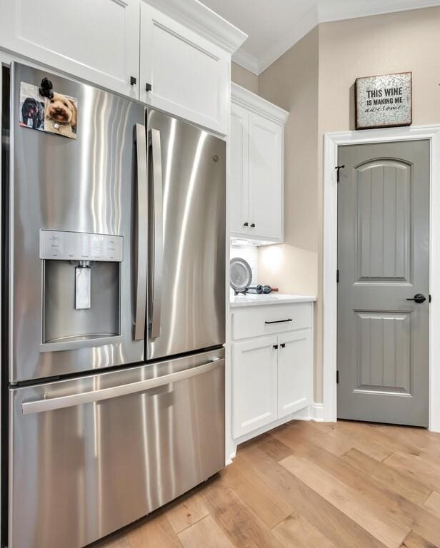 kitchen featuring light wood-type flooring, ornamental molding, white cabinets, and stainless steel refrigerator with ice dispenser