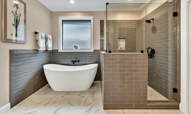 bathroom featuring ornamental molding, separate shower and tub, and tile walls