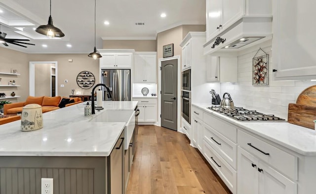 kitchen with white cabinetry, hanging light fixtures, an island with sink, and appliances with stainless steel finishes