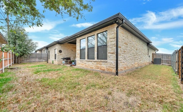 back of house featuring central AC unit and a lawn