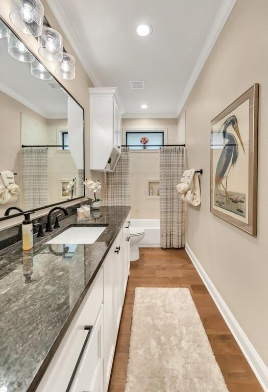 full bathroom with toilet, ornamental molding, shower / bathtub combination with curtain, vanity, and hardwood / wood-style flooring