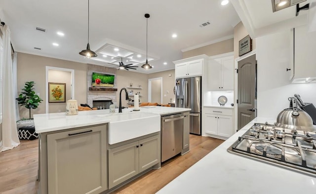 kitchen with sink, appliances with stainless steel finishes, a center island with sink, decorative light fixtures, and light wood-type flooring