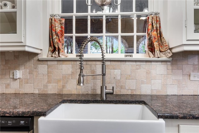 kitchen with dark stone counters, white cabinets, sink, black dishwasher, and tasteful backsplash