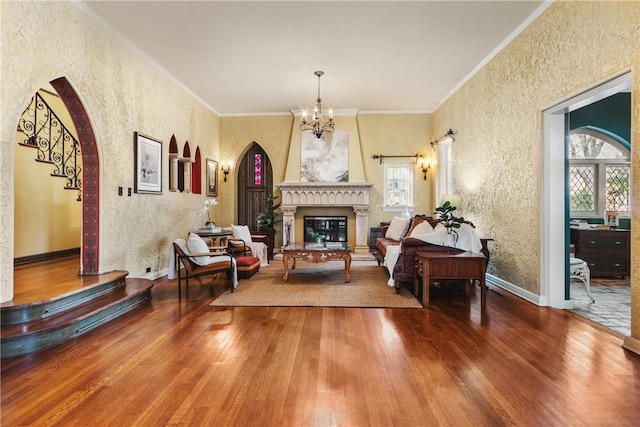 living room featuring wood-type flooring, crown molding, and a notable chandelier