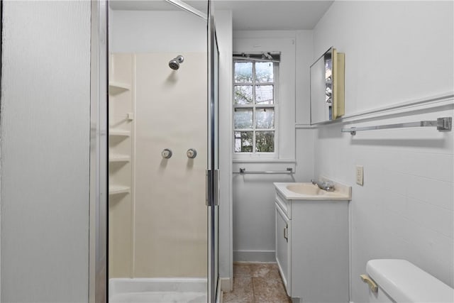 bathroom with a shower, vanity, toilet, and tile walls