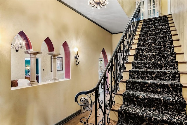 stairs with wood-type flooring, decorative columns, and ornamental molding