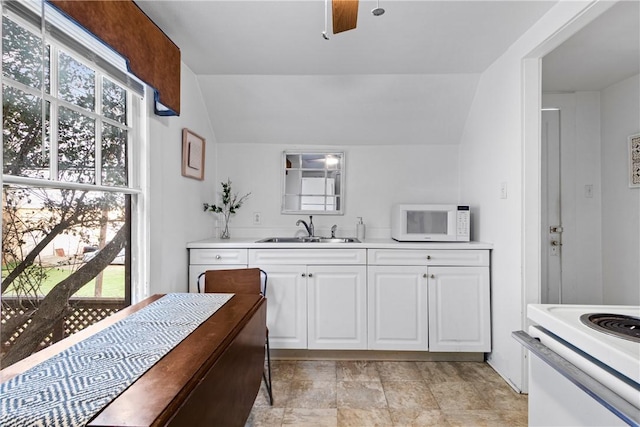 kitchen with white cabinets, white appliances, sink, and vaulted ceiling