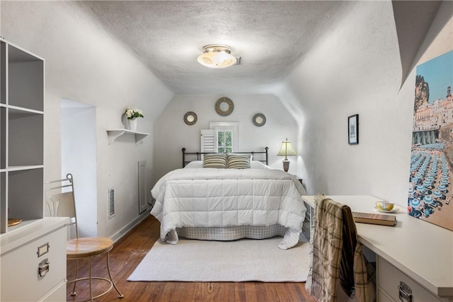 bedroom with a textured ceiling, dark hardwood / wood-style flooring, and vaulted ceiling