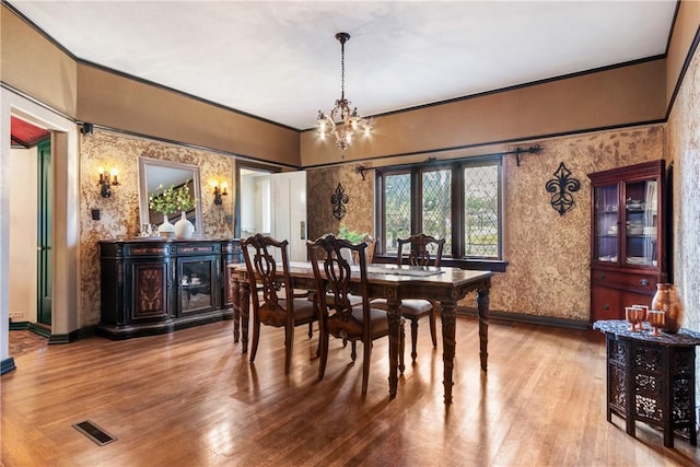 dining room with hardwood / wood-style floors, an inviting chandelier, and ornamental molding