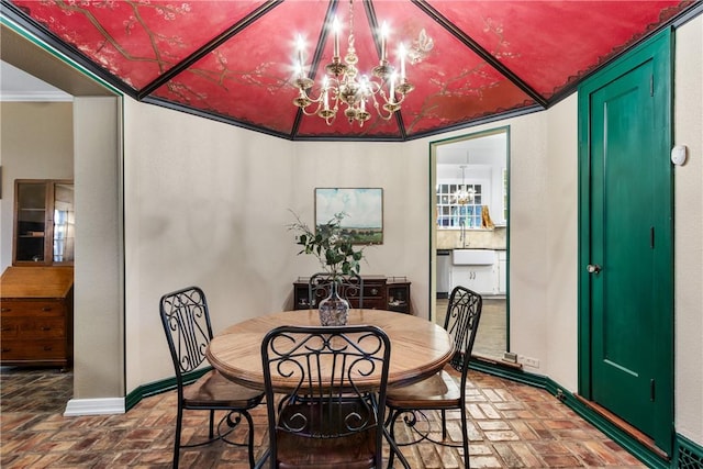 dining space with sink, ornamental molding, and an inviting chandelier