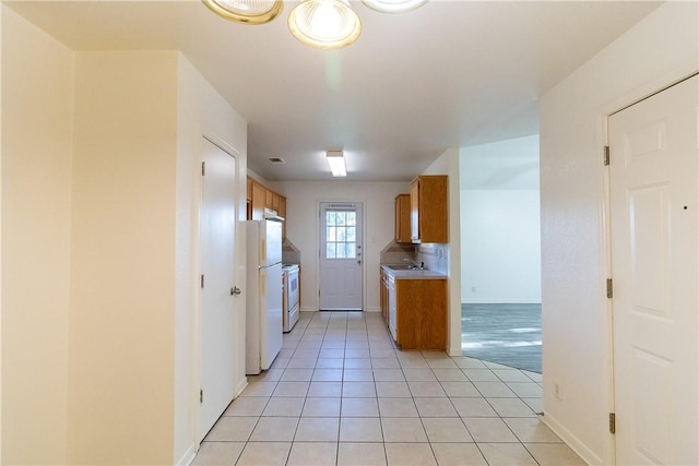 kitchen with sink, light tile patterned floors, and white refrigerator