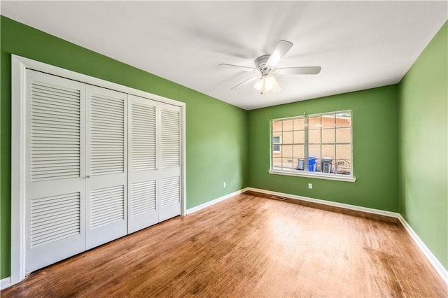 unfurnished bedroom with a closet, hardwood / wood-style flooring, and ceiling fan