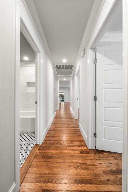 hallway with ornamental molding and dark wood-type flooring