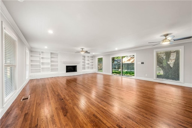 unfurnished living room featuring a fireplace, wood-type flooring, ceiling fan, and crown molding