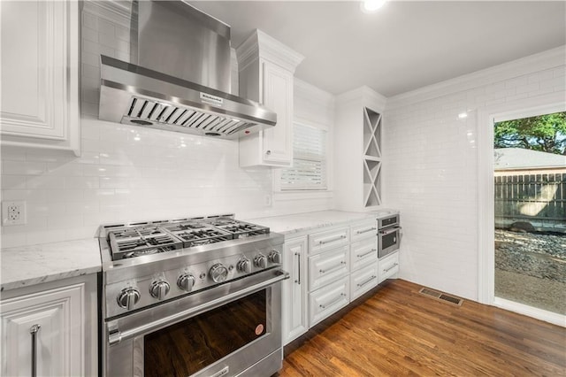 kitchen with white cabinets, wall chimney exhaust hood, dark hardwood / wood-style floors, and appliances with stainless steel finishes