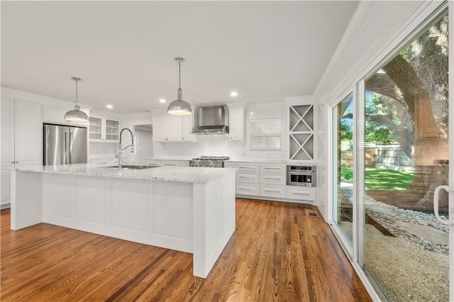 kitchen featuring sink, wall chimney range hood, hanging light fixtures, and appliances with stainless steel finishes