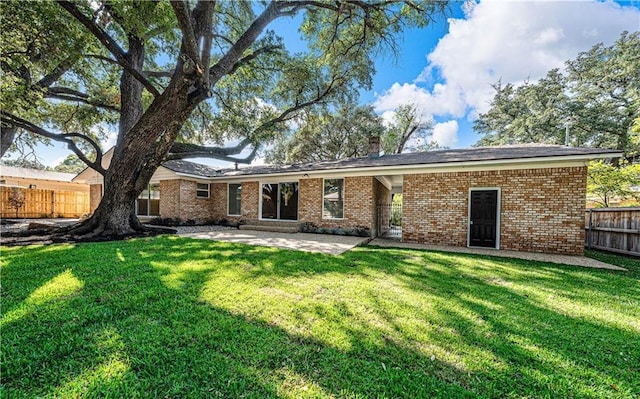 back of property with a lawn and a patio area