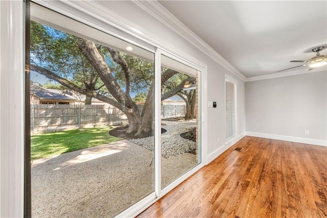 doorway with hardwood / wood-style flooring, ceiling fan, and ornamental molding