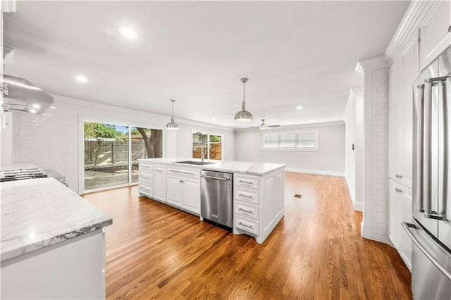 kitchen featuring hardwood / wood-style floors, pendant lighting, wall chimney exhaust hood, appliances with stainless steel finishes, and white cabinetry