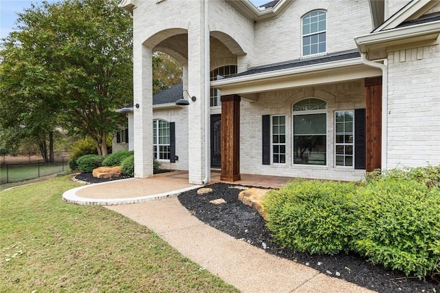 doorway to property featuring covered porch and a lawn