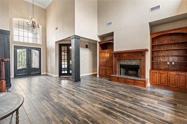 unfurnished living room with french doors, dark hardwood / wood-style flooring, a notable chandelier, and a high ceiling