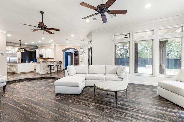 living room with crown molding, ceiling fan, and dark wood-type flooring