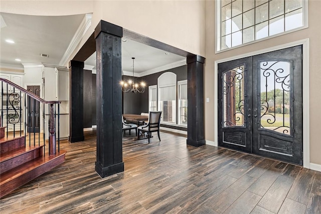 foyer with french doors, a high ceiling, dark hardwood / wood-style flooring, crown molding, and a chandelier