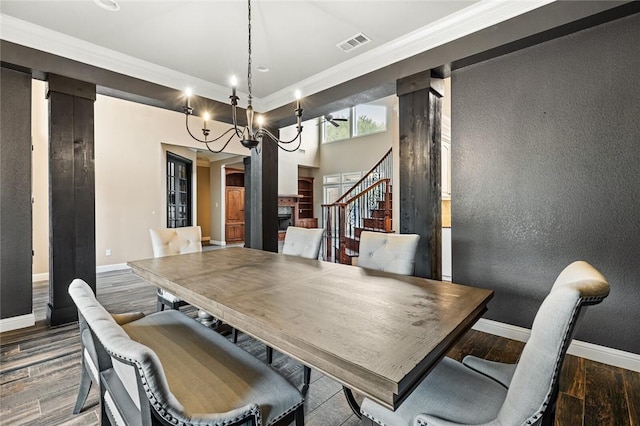 dining room featuring ornate columns, wood-type flooring, a notable chandelier, and ornamental molding