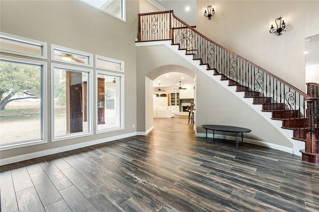 foyer with ceiling fan, a towering ceiling, and dark hardwood / wood-style floors