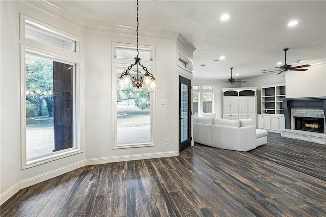 unfurnished living room featuring a healthy amount of sunlight, crown molding, dark wood-type flooring, and a brick fireplace