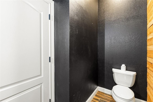 bathroom with wood walls, toilet, and hardwood / wood-style flooring