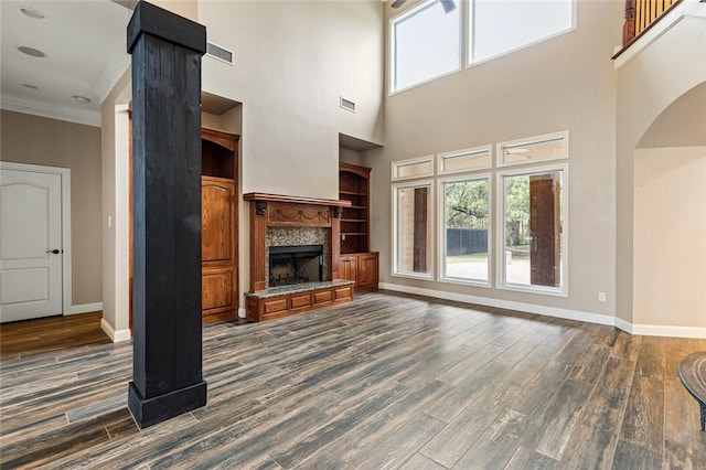 unfurnished living room with a high ceiling, built in features, and dark wood-type flooring