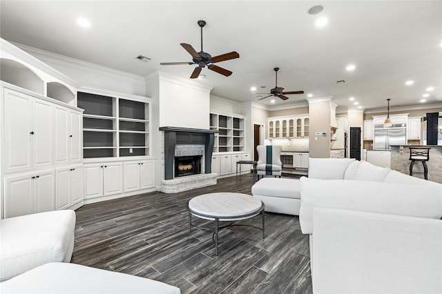 living room with ceiling fan, ornamental molding, dark wood-type flooring, and a brick fireplace