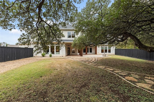 rear view of property featuring a lawn and a patio