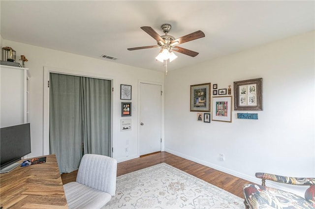 office area with baseboards, visible vents, ceiling fan, and wood finished floors