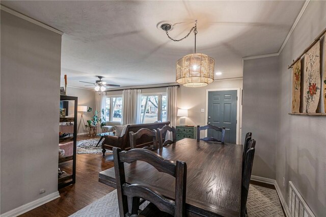 dining area featuring baseboards, visible vents, crown molding, and wood finished floors