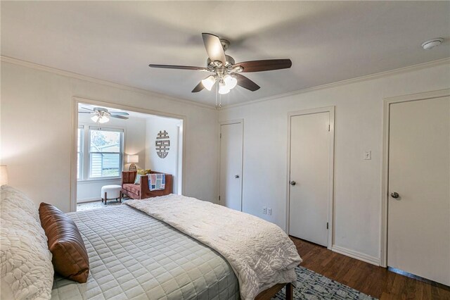 bedroom featuring baseboards, ceiling fan, wood finished floors, crown molding, and two closets